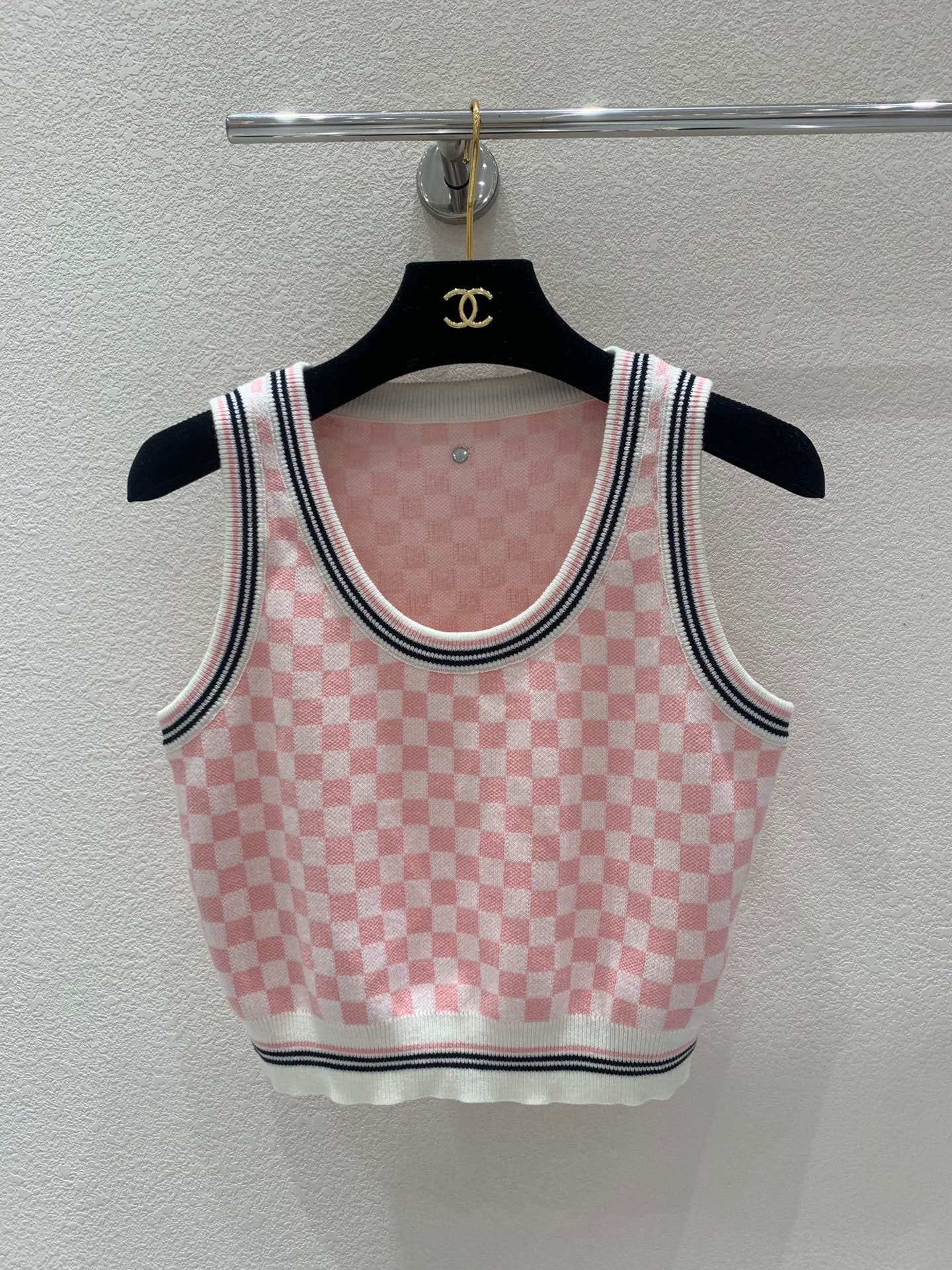 Pink and white checkerboard knit vest with a metal logo clasp on the back