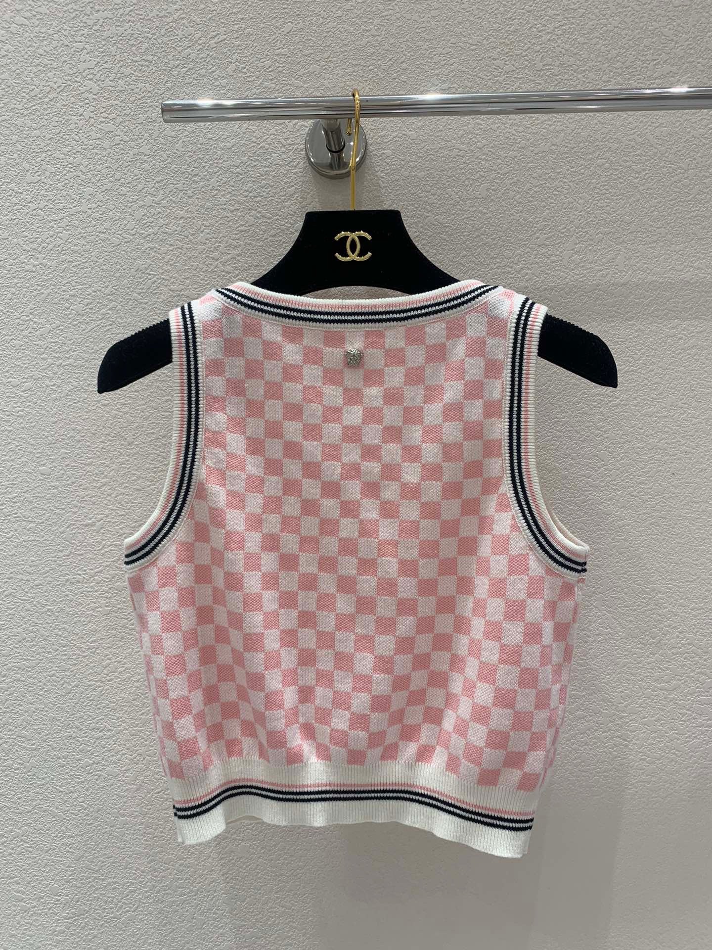 Pink and white checkerboard knit vest with a metal logo clasp on the back