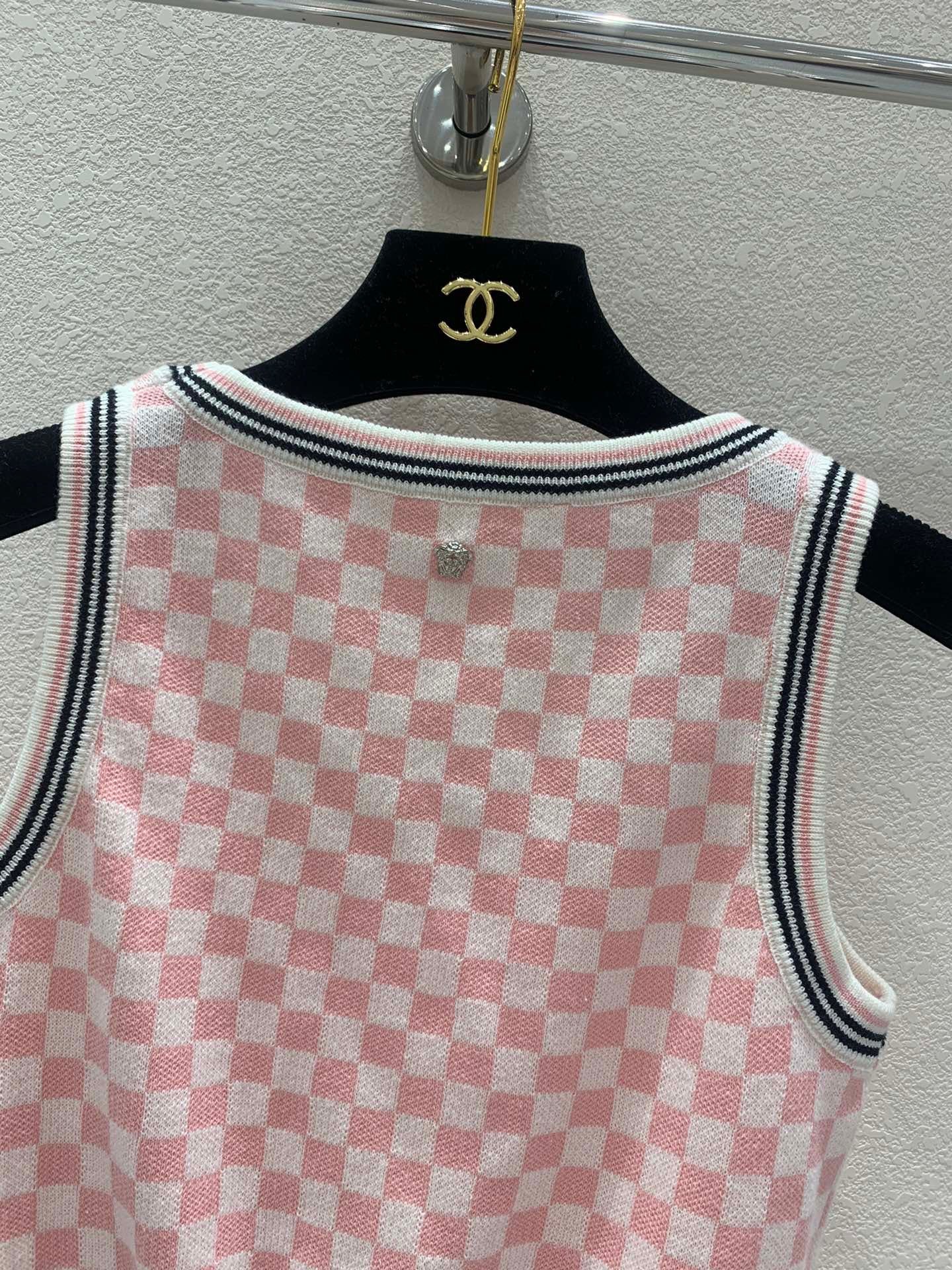 Pink and white checkerboard knit vest with a metal logo clasp on the back